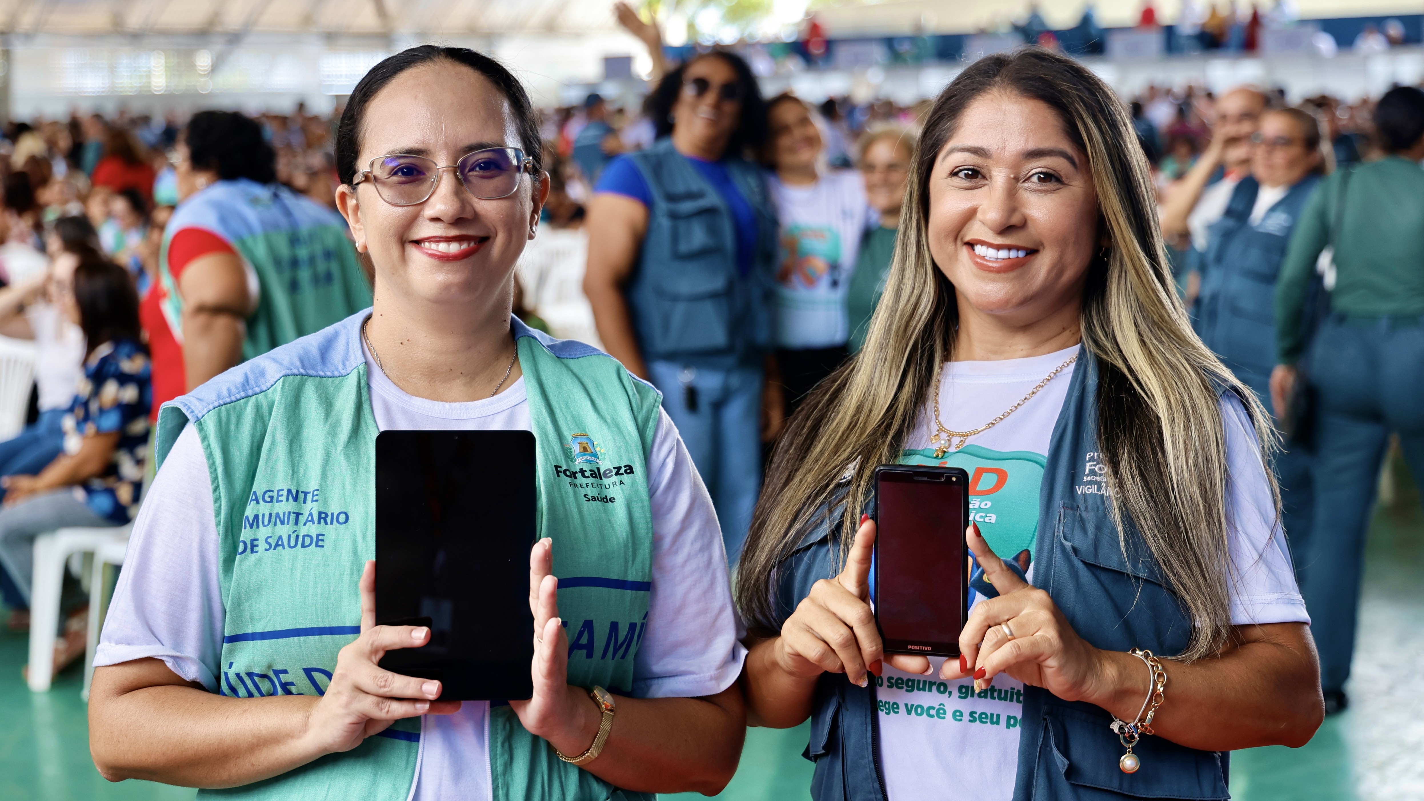 Uma  agentes de saúde e uma agente de combate às endemias posam para a foto com um tablet e um celular 